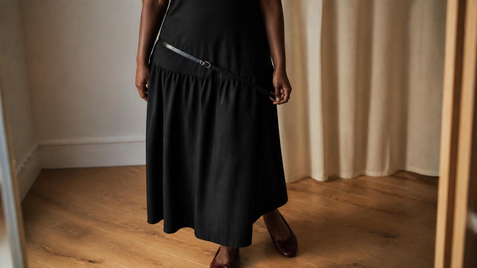 Drop waist black midi dress styled with a low leather belt and burgundy flats.